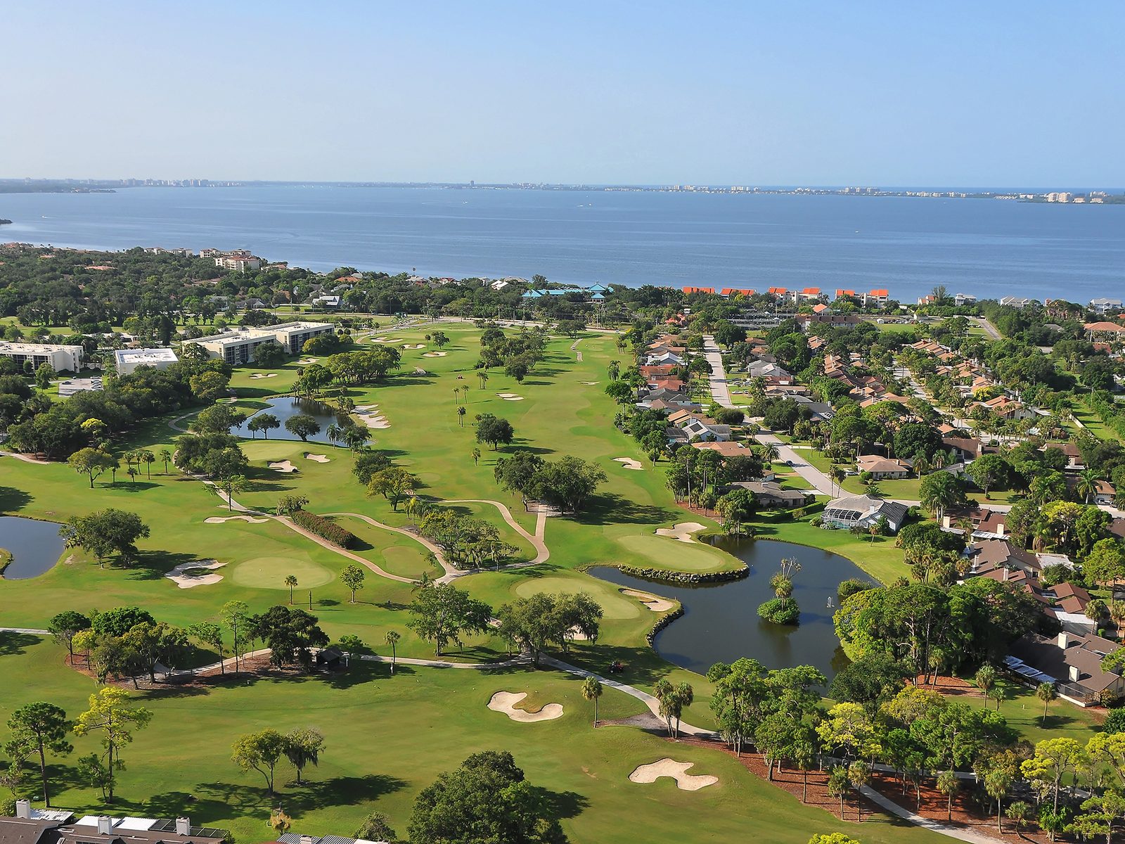 Aerial view of a West Bradenton golf course with fairway homes and Sarasota Bay beyond